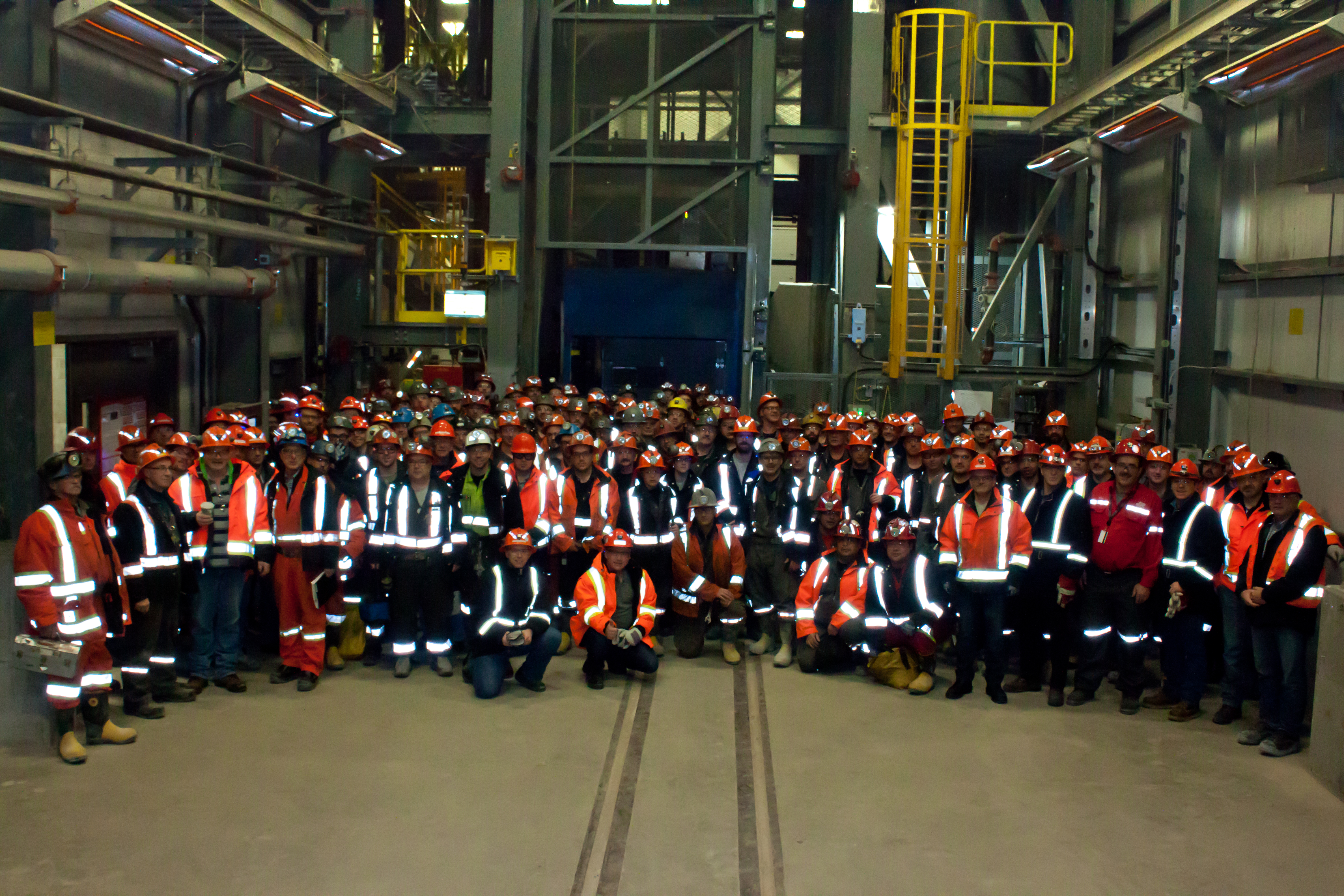 A large group of employees pose underground.